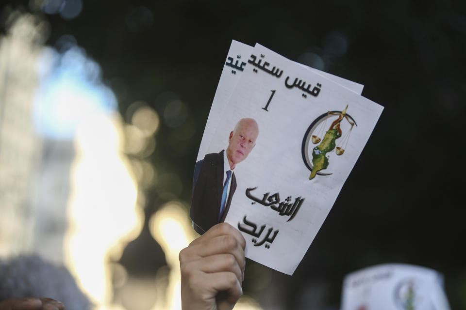 A supporter of independent Tunisian Presidential candidate Kais Saied carries pamphlets as he attends a rally on the last day of campaigning before the second round of the presidential elections, in Tunis, Tunisia, Friday, Oct. 11, 2019. Poster in Arabic shows the number and slogan of Kais "People's wish." (AP Photo/Mosa'ab Elshamy)