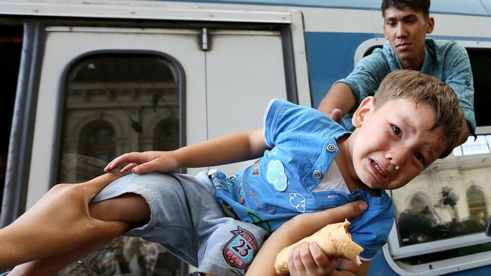 Niño alzado tratando de entrar en tren