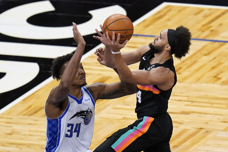 San Antonio Spurs guard Derrick White, right, takes a shot over Orlando Magic center Wendell Carter Jr. (34) during the first half of an NBA basketball game, Monday, April 12, 2021, in Orlando, Fla. (AP Photo/John Raoux)