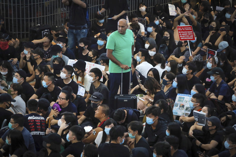 A traveler stands amidst protesters during a sit-in rally at the Airport in Hong Kong, Tuesday, Aug. 13, 2019. (Photo: Kin Cheung/AP)