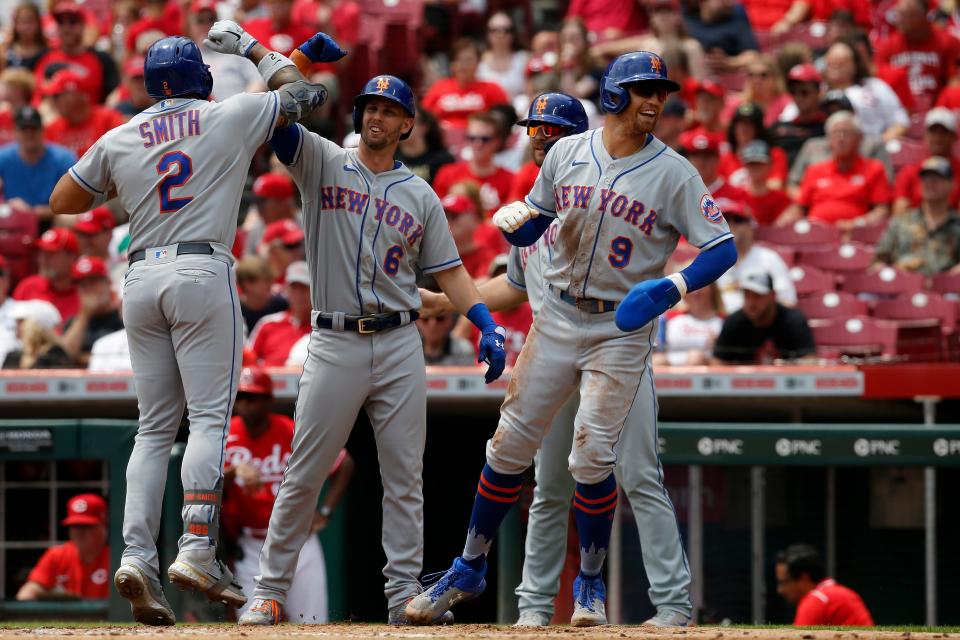 The Mets celebrate after scoring on a grand slam home run off the bat of New York Mets first baseman Dominic Smith (2) in the third inning of the MLB National League game between the Cincinnati Reds and the New York Mets at Great American Ball Park in downtown Cincinnati on Wednesday, July 21, 2021.