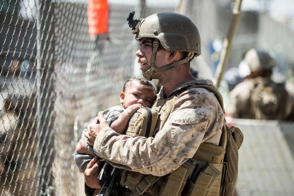 PHOTO: A Marine with Special Purpose Marine Air-Ground Task Force-Crisis Response-Central Command calms a child during an evacuation at Hamid Karzai International Airport in Kabul, Afghanistan, Aug. 26, 2021. (Sgt. Samuel Ruiz/U.S. Marine Corps via AP, FILE)