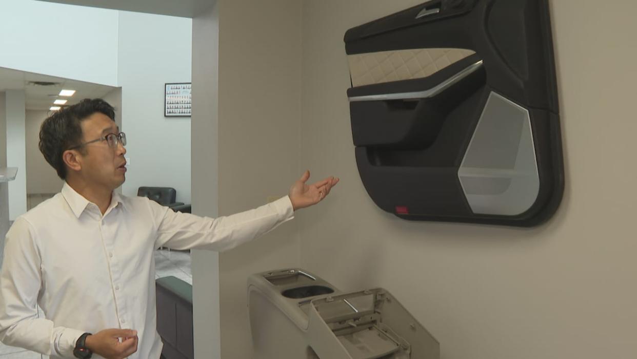 CAMM Chair Saylo Lam points to a door panel his firm Circle 5 creates the mold for. (Dale Molnar/CBC - image credit)