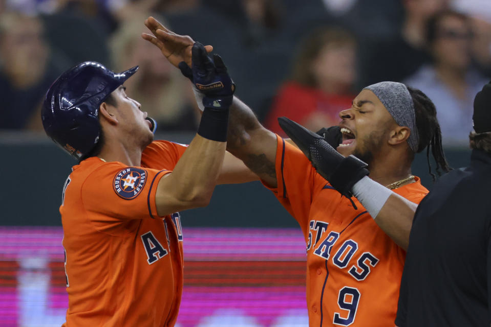 Houston Astros Mauricio Dubon, left, and Corey Julks, right, celebrate scoring on a triple from Chas McCormick in the eighth inning of a baseball game against the Texas Rangers, Sunday, July 2, 2023, in Arlington, Texas. (AP Photo/Gareth Patterson)