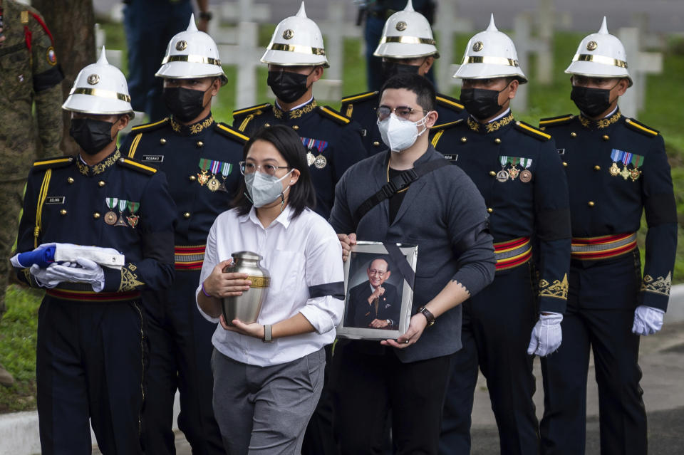 Grandchild of former Philippine President Fidel Ramos carries his urn during his state funeral at the Heroes' Cemetery in Taguig City, Philippines, Tuesday, Aug. 9, 2022. Ramos was laid to rest in a state funeral Tuesday, hailed as an ex-general, who backed then helped oust a dictatorship and became a defender of democracy and can-do reformist in his poverty-wracked Asian country. (Lisa Marie David/Pool Photo via AP)