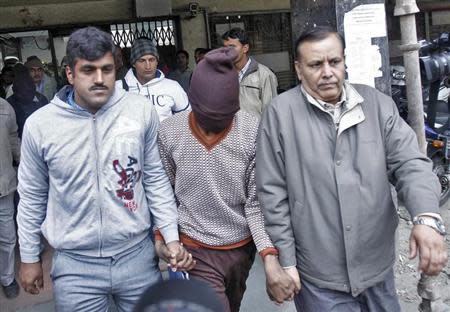 Plain-clothes police escort men (face covered) accused of a gang rape outside a court in New Delhi January 16, 2014. REUTERS/Anindito Mukherjee/Files