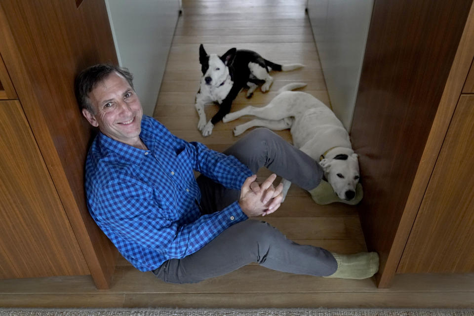 Leonard Goodman, co-owner of the Chicago Reader weekly newspaper sits in his home for a portrait with his dogs Lucy and Poncho, Tuesday, May 10, 2022, in Chicago. The Reader is expected to become a nonprofit this month after the sale was nearly derailed over Goodman's column opposing COVID-19 vaccine requirements for children. Goodman said the Reader should have stood by him once the piece was published, despite disagreement about his point of view. "This is an opinion piece," he said. "It's not writing as a scientist." (AP Photo/Charles Rex Arbogast)