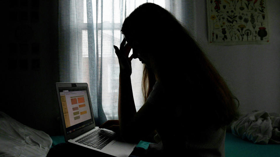 In this photo illustration, we see a silhouette of a teenager posing with a laptop, looking stressed out.