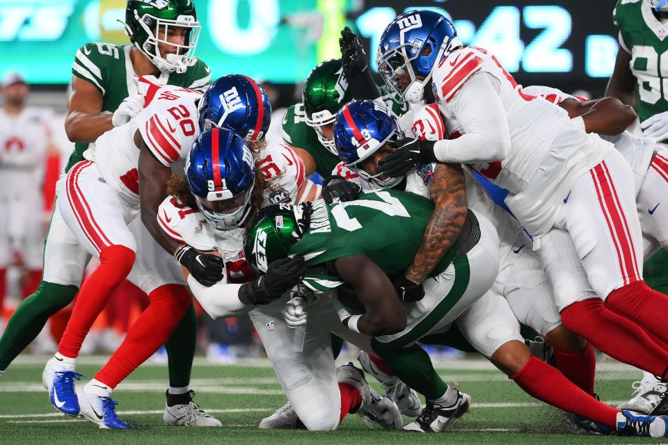 Aug 24, 2024; East Rutherford, New Jersey, USA; New York Giants defensive tackle Casey Rogers (91) tackles New York Jets running back Israel Abanikanda (25) with help from a host of teammates during the first half at MetLife Stadium. Mandatory Credit: Rich Barnes-USA TODAY Sports