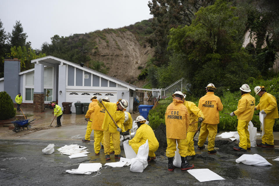 California Department of Corrections prisoners help sandbag homes along Gotera Drive in the Hacienda Heights section of Los Angeles on Tuesday, Feb. 6, 2024. (AP Photo/Marcio Jose Sanchez)