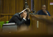 Oscar Pistorius covers his head with his hands and a notebook as he listens to forensic evidence during his trial in court in Pretoria, South Africa, Thursday March 13, 2014. Pistorius is charged with the shooting death of his girlfriend Reeva Steenkamp on Valentines Day in 2013. (AP Photo/Alet Pretorius, Pool)
