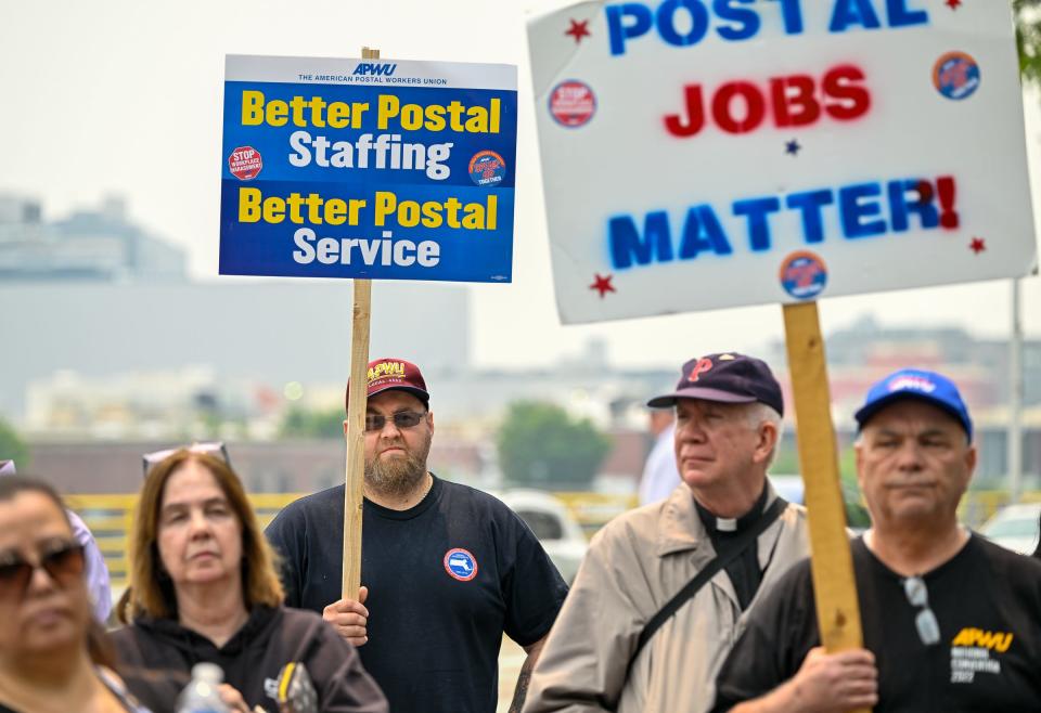 Keith Richards, left, from Central Mass., holds a sign as he listens to speeches during a rally to prevent privatization of the post office Tuesday outside the U.S. Post Office in Boston.