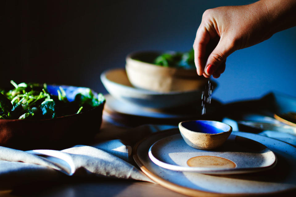 Woman sprinkling salt in bowl while preparing a salad  (Cavan Images / Getty Images)