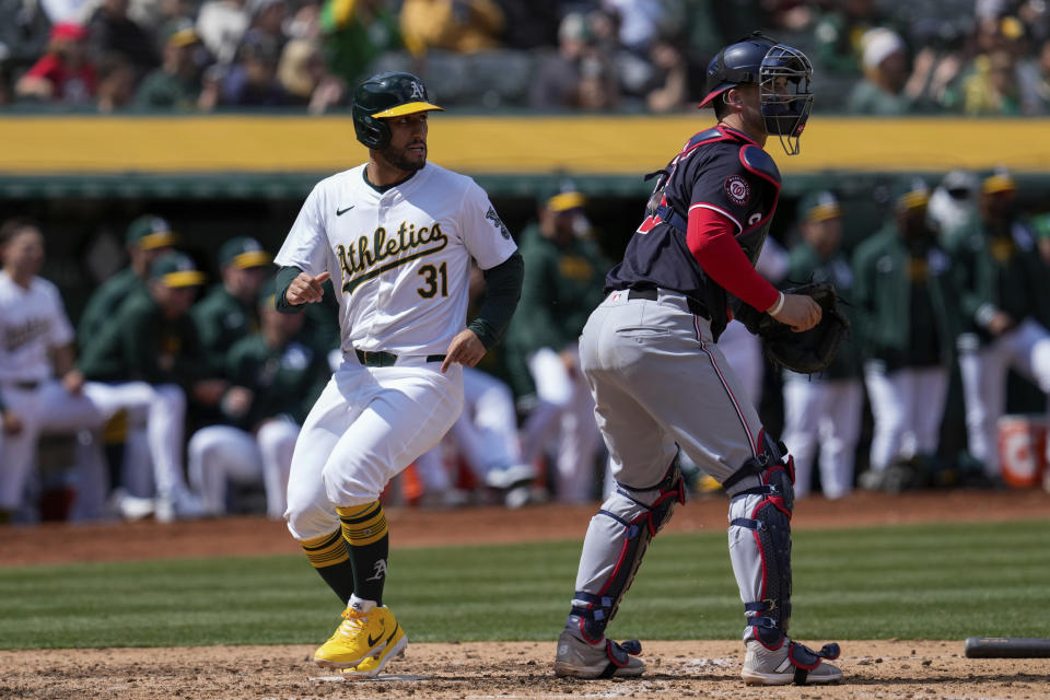 Oakland Athletics' Abraham Toro, left, scores next to Washington Nationals catcher Riley Adams on Tyler Nevin's single during the sixth inning of a baseball game ,Sunday, April 14, 2024, in Oakland, Calif. (AP Photo/Godofredo A. Vásquez)