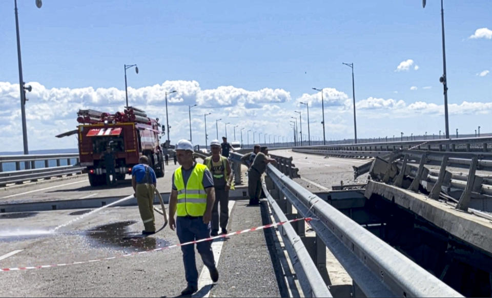 In this image from a video released on Wednesday, July 19, 2023 by Russian National Antiterrorism Committee, employees work at the damaged parts of an automobile link of the Crimean Bridge connecting Russian mainland and Crimean peninsula over the Kerch Strait not far from Kerch, Crimea. (Russian National Antiterrorism Committee via AP)