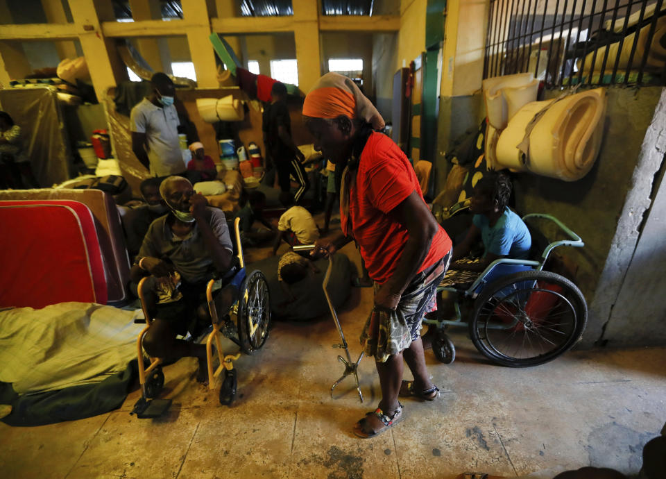 Displaced Haitians wait for breakfast to be served by volunteers, at a shelter in Port-au-Prince, Haiti, Saturday, July 10, 2021, three days after Haitian President Jovenel Moise was assassinated in his home. Among those forced to flee their homes, that were set on fire in late June by armed gangs, are dozens of disabled people who were injured in the 2010 earthquake. (AP Photo/Fernando Llano)