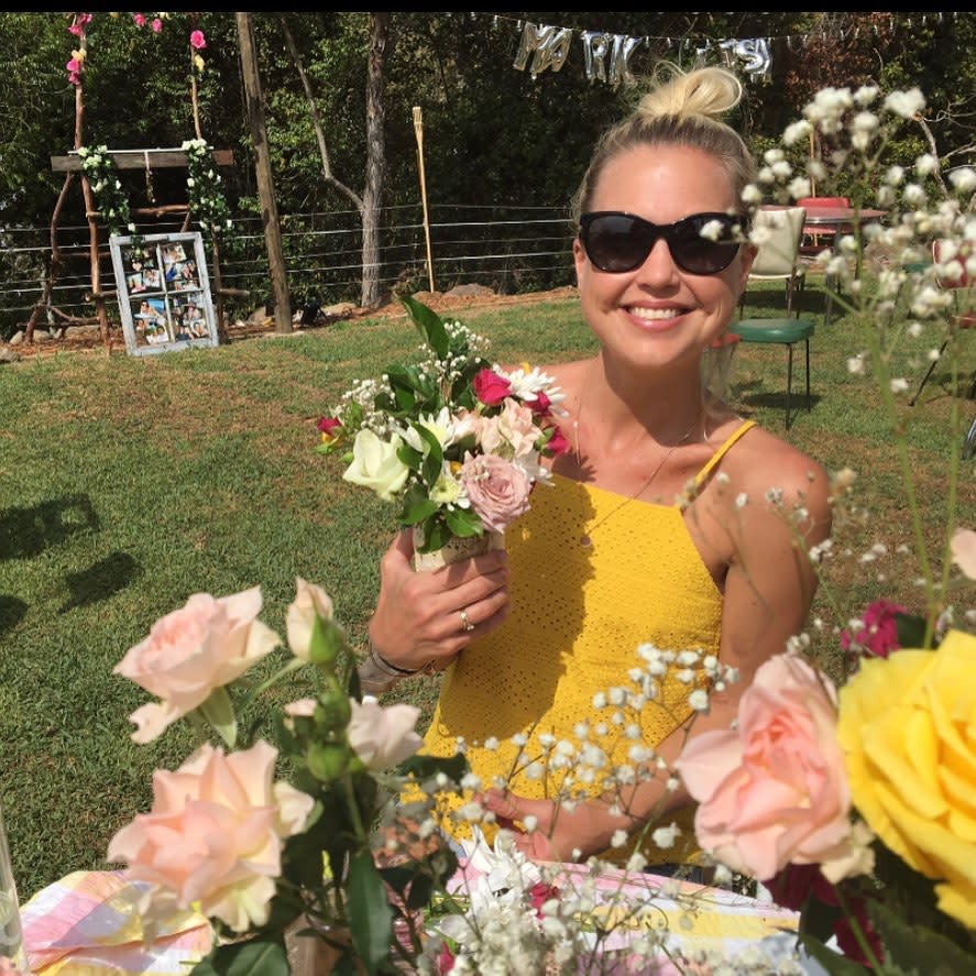 Jaimi Curry Kenny surrounded by flowers wearing a yellow dress