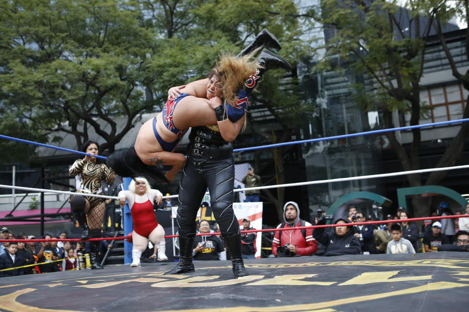 Mexican female wrestlers Amazona and Brillo de Luna clash during a "lucha libre" public fight in Mexico City, Saturday, Dec. 21, 2019. Mexican wrestling, otherwise known as the “lucha libre,” is a highly traditional form of light entertainment masquerading as a ‘sport’. (AP Photo/Ginnette Riquelme)