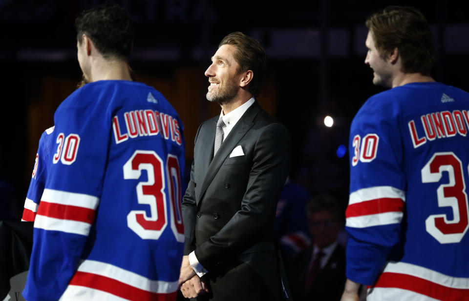 Former New York Rangers goaltender Henrik Lundqvist, center, watches as his number is retired before an NHL hockey game between the New York Rangers and the Minnesota Wild Friday, Jan. 28, 2022 in New York. He was joined on the ice by current Rangers players wearing his jersey. (AP Photo/John Munson)