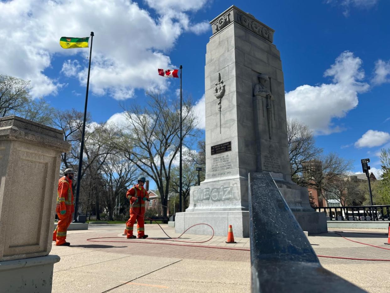 Crews could be seen removing vandalism reading 'Save Gaza' from the Regina Cenotaph early Thursday morning. Police say they are investigating the vandalism, which is part of a series of tags the premier called 'disgusting' and 'anti-Semitic.' (Will Draper/CBC - image credit)