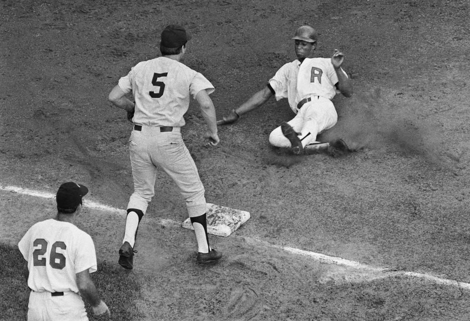 Red Wings center fielder Rich Coggins slides safely into third base during the Wings game against Syracuse on Sept. 1, 1971 at Frontier Field.  The Wings would win the game 7-5.  Looking on is Red Wings manager Joe Altobelli (26). 