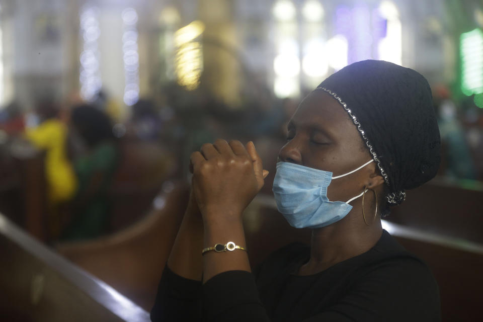 A woman wearing a face mask to protect against COPVID-19, prays during a morning Christmas Mass at Holy Cross Cathedral in Lagos, Nigeria, Saturday Dec. 25, 2021. (AP Photo/Sunday Alamba)