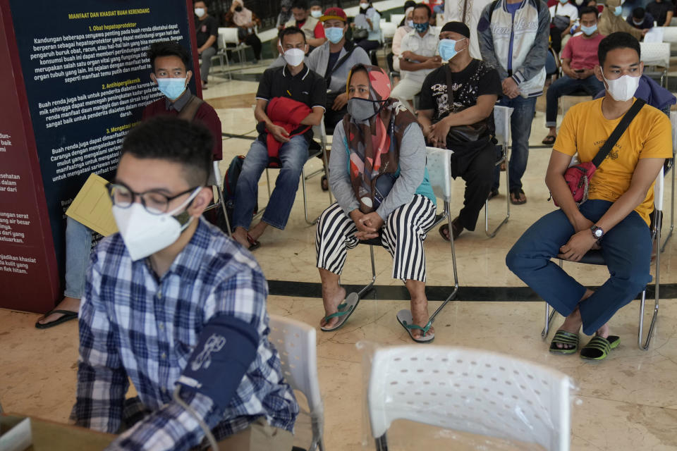 People wait for health screenings required before they receive the Sinovac vaccine for COVID-19 during a mass vaccination in Jakarta, Indonesia, Monday, June 21, 2021. Indonesia's president ordered authorities to speed up the country's vaccination campaign as the World Health Organization warned of the need to increase social restrictions in the country amid a fresh surge of coronavirus infections caused by worrisome variants. (AP Photo/Dita Alangkara)