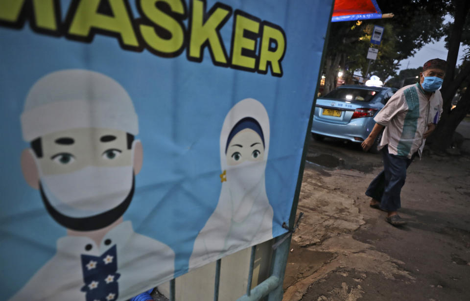 A man walks past a banner with a message encouraging people to always wear masks to help curb the spread of coronavirus outbreak, in Jakarta, Indonesia, Thursday, Dec. 3, 2020. (AP Photo/Dita Alangkara)