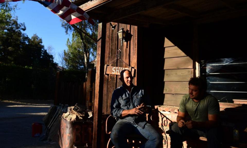 Morgan Runyon sits with a friend on the porch of his restaurant The Old Place after ignoring evacuation orders to stay behind and save the restaurant from the Woolsey fire.