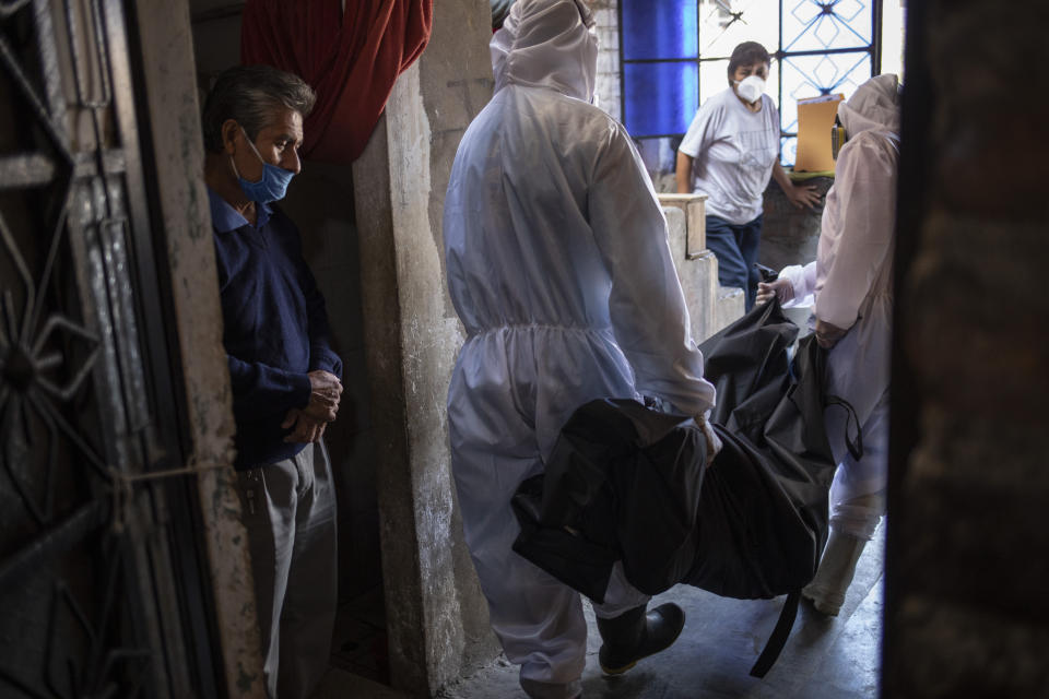 Teodoro Mejía (izq) observa a personal de la funeraria Piedrangel que se lleva el cadáver de su esposa Berta Cusi Palomino en su casa de Lima el 14 de mayo del 2020. Mejía cree que su esposa murió por el coronavirus. (AP Photo/Rodrigo Abd)