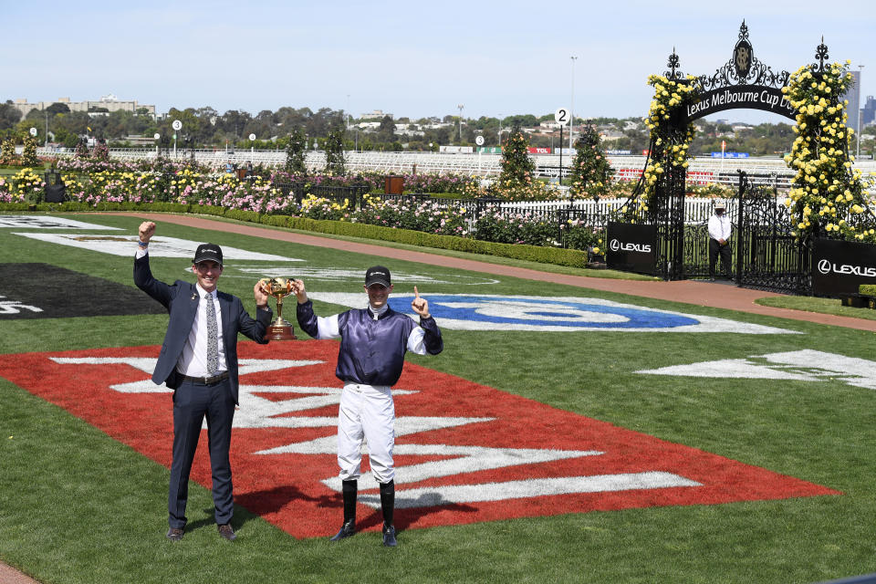 Twilight Payment's assistant trainer Mark Power, let, and jockey Jye McNeil pose with the trophy after winning the Melbourne Cup horse race at Flemington Racecourse in Melbourne, Australia, Tuesday, Nov. 3, 2020. (AP Photo/Andy Brownbill)