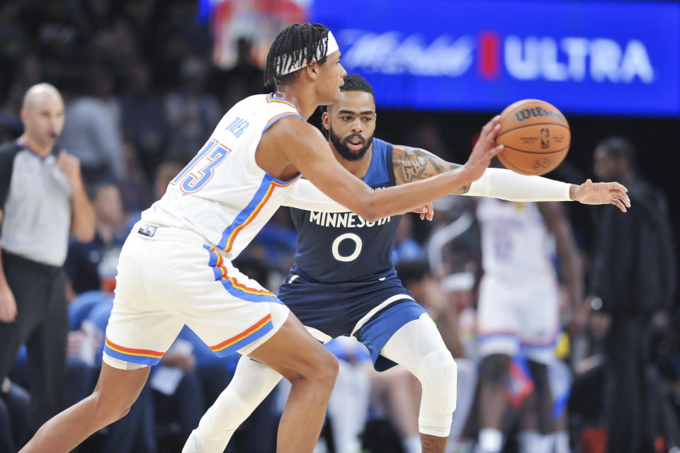 Oklahoma City Thunder forward Ousmane Dieng passes the ball around Minnesota Timberwolves guard D'Angelo Russell (0) in the second half of an NBA basketball game, Sunday, Oct. 23, 2022, in Oklahoma City. (AP Photo/Kyle Phillips)