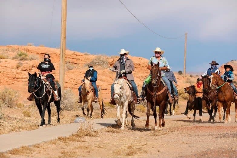 Allie Young, left, a Diné woman on the Navajo Nation in Arizona, is among a group of Native Americans as they ride on horseback to the polls on Election Day (AP)