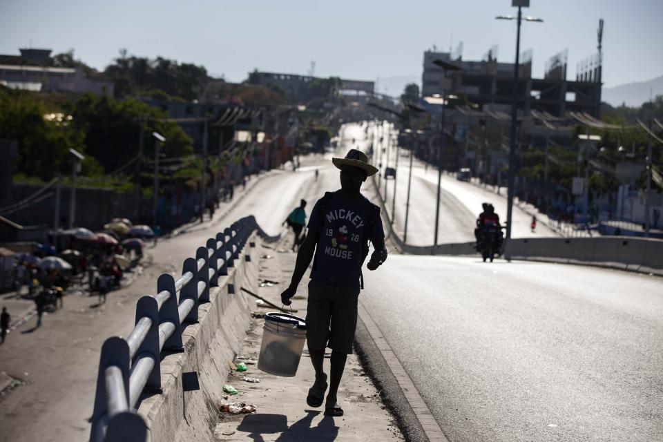 A man walks toward downtown along the main street of Delmas, devoid of cars due to a nationwide strike demanding the resignation of Haitian President Jovenel Moise in Port-au-Prince, Haiti, Monday, Feb. 1, 2021. Opposition leaders are pushing for Moïse to step down on Feb. 7 while Moïse has said his term ends in February 2022. (AP Photo/Dieu Nalio Chery)