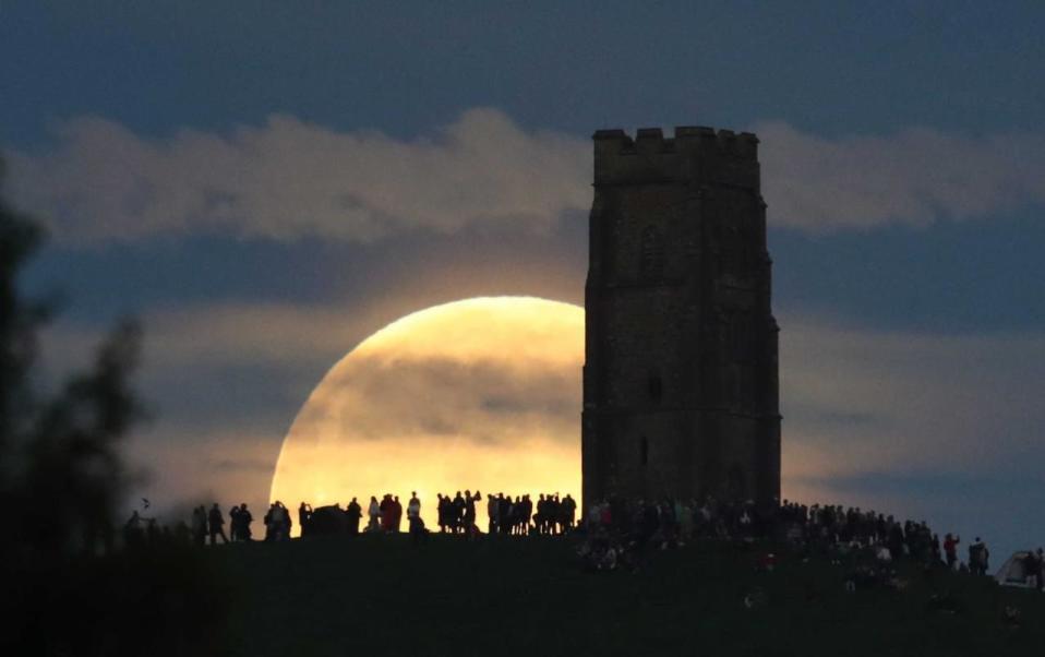 A full moon rises behind Glastonbury Tor as people gather to celebrate the summer solstice on June 20, 2016 in Somerset, England. (Photo by Matt Cardy/Getty Images)