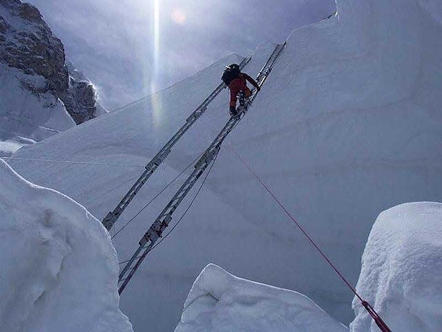 A climber climbs a ladder at the Khumbu Icefall