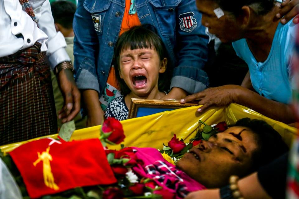 A little girl wails over the open casket of her father