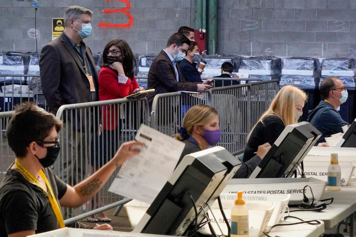 Election observers stand behind a barrier and watch as election office workers process ballots as counting continues from the general election at the Allegheny County elections returns warehouse in Pittsburgh on 6 November. (AP)
