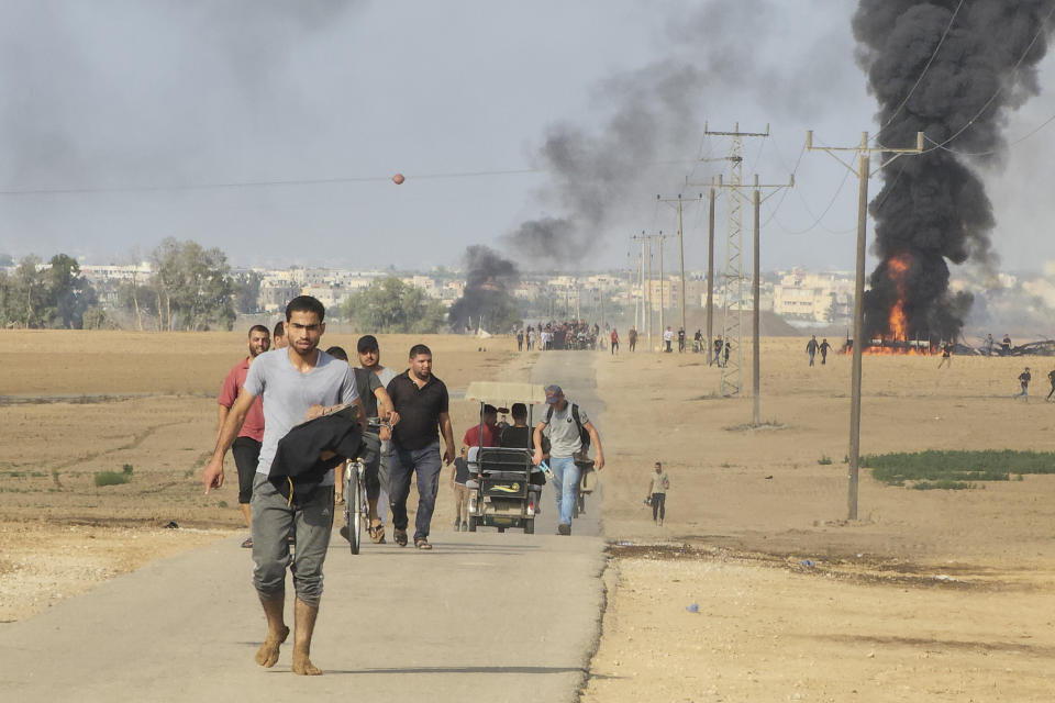 Palestinos se alejan del kibbutz de Kfar Azza, Israel, cerca de la valla fronteriza de la Franja de Gaza, el 7 de octubre de 2023. (AP Foto/Hassan Eslaiah)