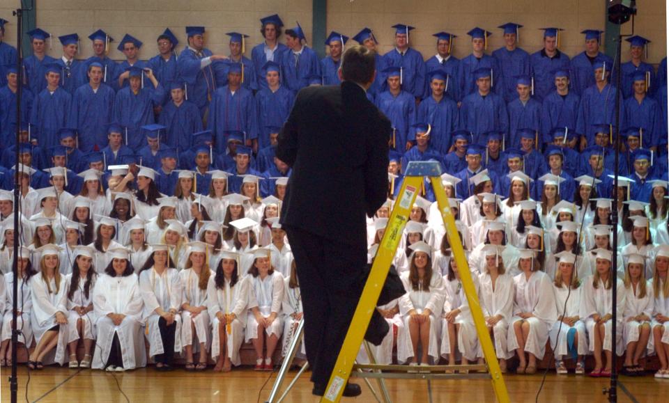 Tom Davis, of Northern Image Photography on Cape Cod, attempts to get members of the Middletown High School graduating class to smile before their commencement ceremony on June 15, 2003.