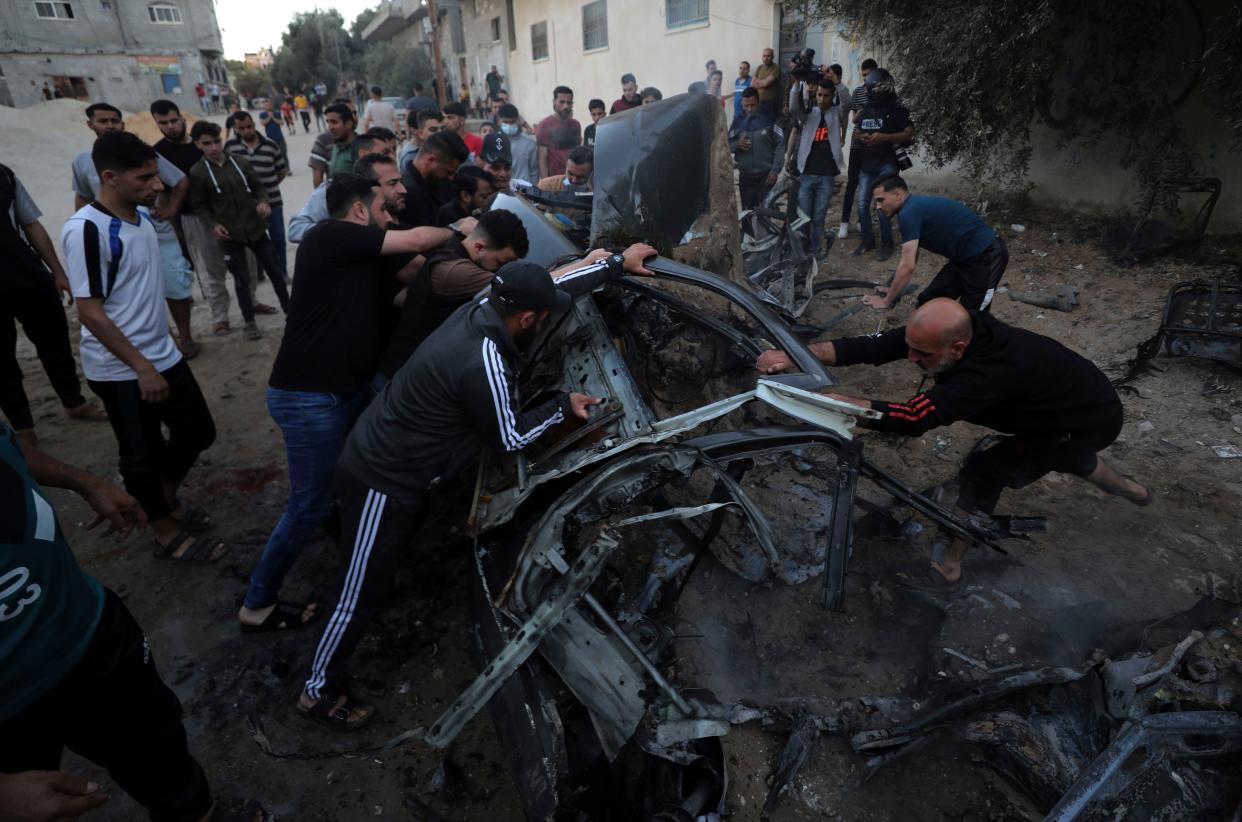 Palestinians gather around a car after it was hit by an Israeli airstrike in Gaza City on Saturday, May 15, 2021.