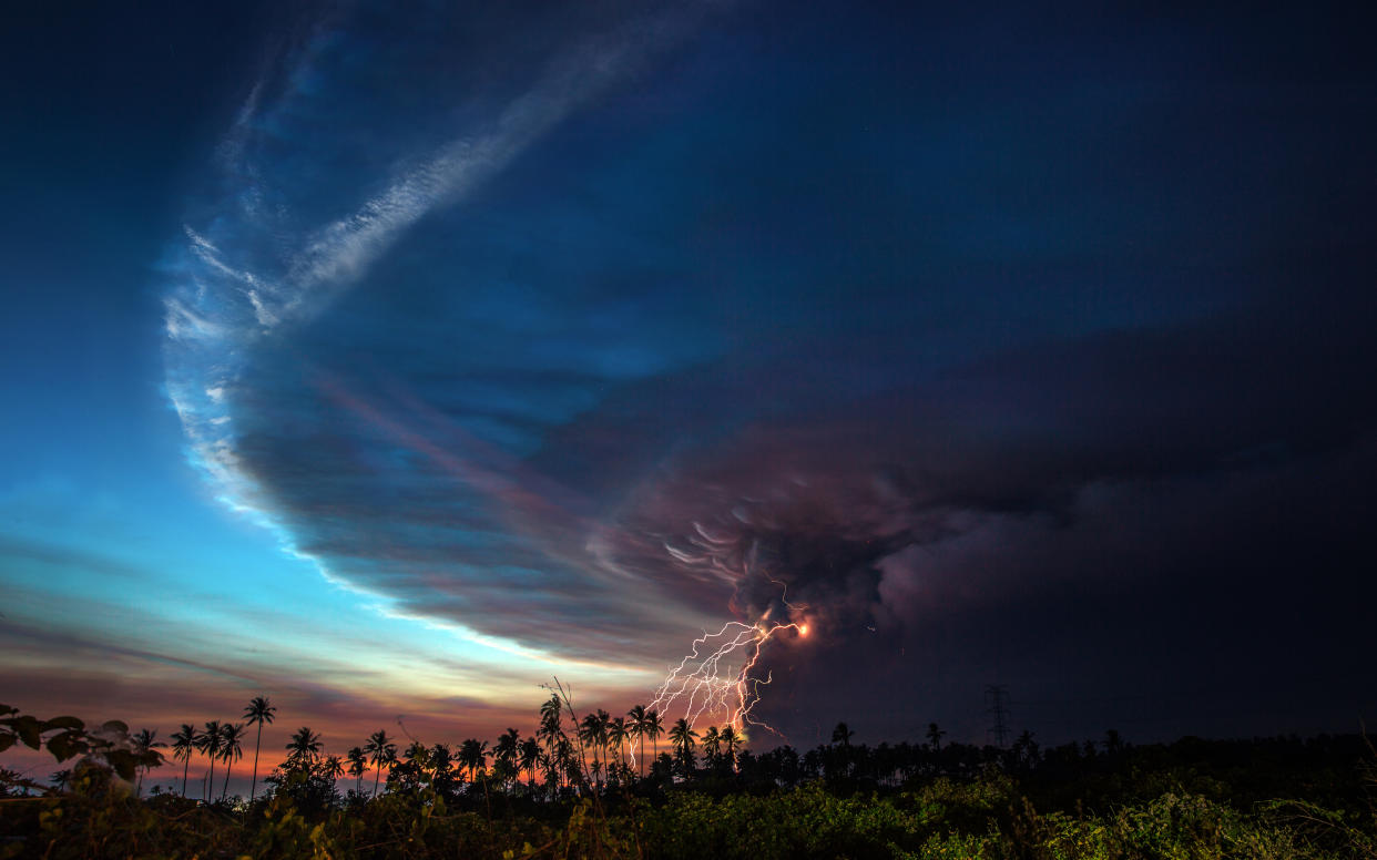 BATANGAS PROVINCE, PHILIPPINES - 2020 JANUARY 12: The evening sky with volcanic lightning, the eruption of Taal Volcano as seen from the nearby province of Quezon. The eruption has sent a kilometer plume above the crater, according to the Philippine Institute of Volcanology and Seismology. Tens of thousands of people are evacuating near the capital of the Philippines. Due to level 4 alert, government officials implemented preemptive evacuations in all nearby communities.