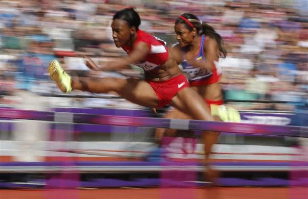 Kellie Wells of the U.S. (L) and Colombia's Lina Florez compete in their women's 100m hurdles round 1 heat during the London 2012 Olympic Games at the Olympic Stadium August 6, 2012.