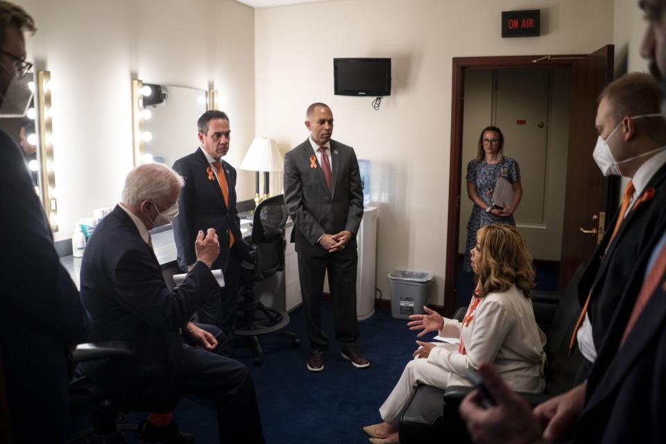 Several lawmakers speaking in a room offstage before a news conference