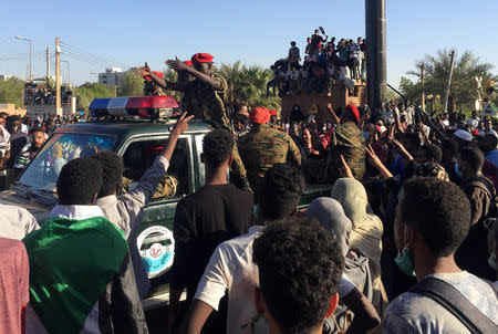 Sudanese demonstrators flash the victory sign as a military police vehicle drives past them during a protest demanding Sudanese President Omar Al-Bashir to step down in Khartoum, Sudan April 6, 2019. REUTERS/Stringer