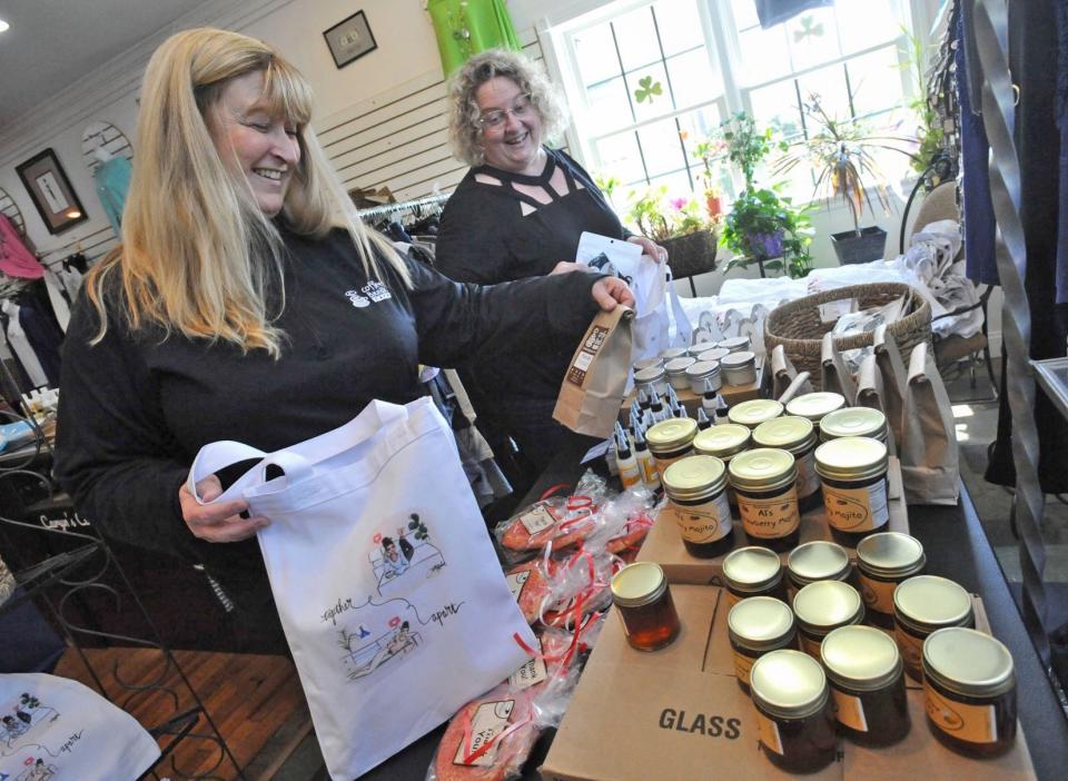 Jenn Ormond, left, and Caryn Smith, both of Quincy, pack South Shore Survival Bags that sell for $75 to support local businesses and food pantries. (Tom Gorman/For The Patriot Ledger)