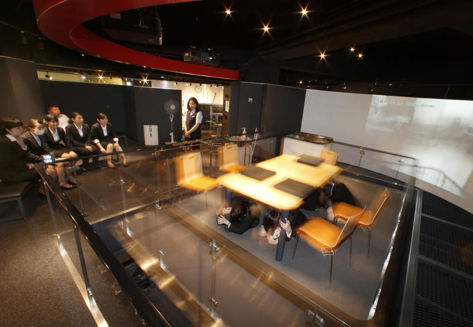 In this photo taken Wednesday, May 29, 2013, visitors take refuge under a table as they experience a temblor at the Ikebukuro Disaster Prevention Center in Tokyo. Japan is one of the most earthquake-prone countries in the world. This public facility, run by the Tokyo Fire Department, offers a uniquely Japanese experience that can be educational, a bit scary but also fun. Visitors can experience a temblor - as violent as the March 2011 disaster that struck northern Japan - in a quake simulator built in a living room set. (AP Photo/Shizuo Kambayashi)