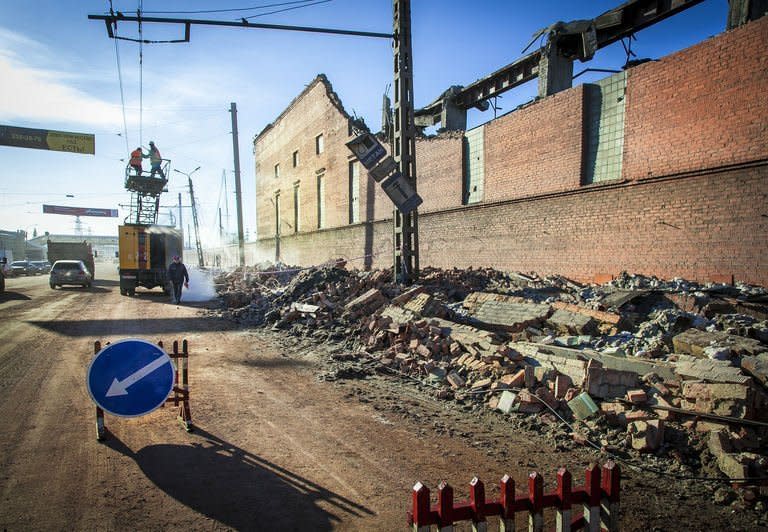 Workers repair a power line near the wall of a zinc plant damaged by a shockwave from a meteor in the Urals city of Chelyabinsk, on February 15, 2013