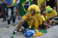 <p>Brazil soccer fans sit dejectedly on the ground as they watch a live telecast of the Brazil vs. Belgium World Cup quarter finals soccer match, in Rio de Janeiro, Brazil, Friday, July 6, 2018. (AP Photo/Silvia Izquierdo) </p>