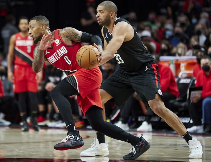 Portland Trail Blazers guard Damian Lillard, left, dribbles past Los Angeles Clippers forward Nicolas Batum during the second half of an NBA basketball game in Portland, Ore., Friday, Oct. 29, 2021. (AP Photo/Craig Mitchelldyer)